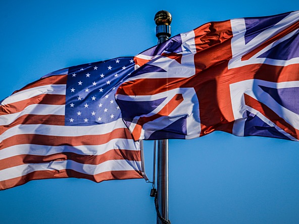 Flags of the United States and the United Kingdom flying against a blue sky 